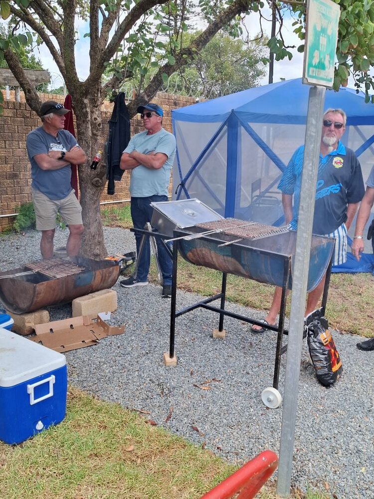 Wild Buggers club members chatting around a drum braai while grilling boerewors for the Goue Aar charity lunch.