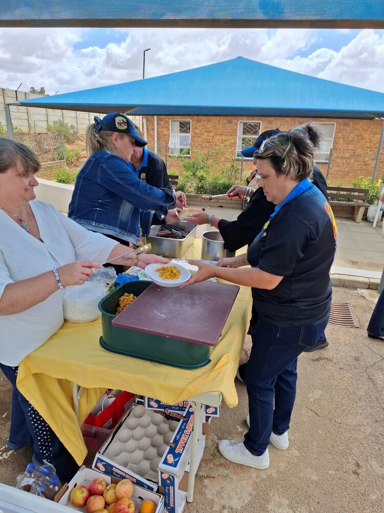 Wild Buggers Ladybugs dishing up fresh pasta salad and boerewors rolls for the residents at Goue Aar.