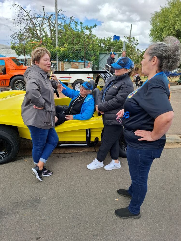 A group of Wild Buggers Beach Buggy Club members having a final chat around a yellow beach buggy before departing from the Goue Aar charity event.