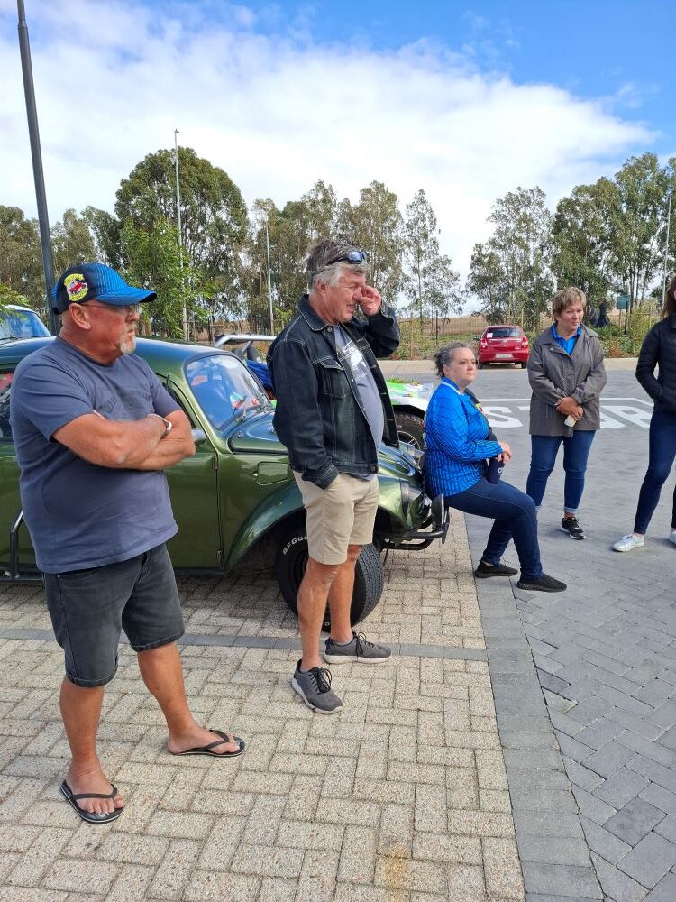 Wild Buggers club members holding a briefing session next to a green VW Beetle and custom Beach Buggies before the charity convoy.