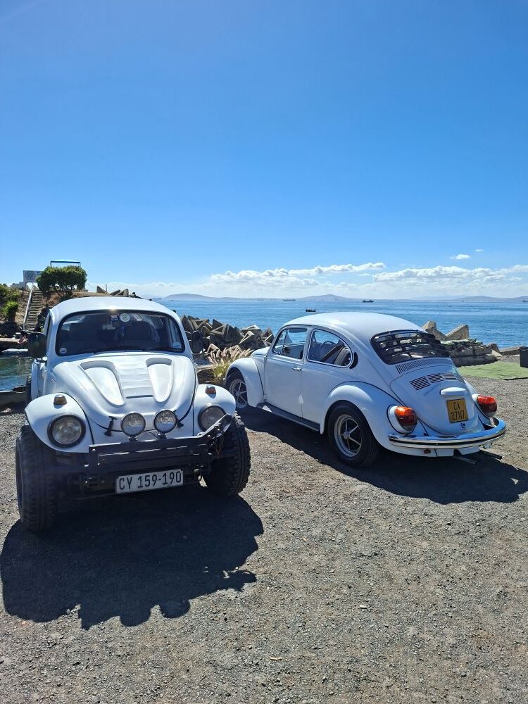 A rugged white VW Baja Bug and Andre and Jo-ann Gericke’s classic 1975 white VW Beetle parked at the Oceana Power Boat Club in Cape Town.