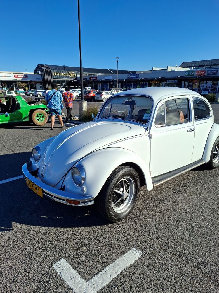 A classic white Volkswagen Beetle parked at Bothasig Square during a Wild Buggers Beach Buggy Club event in Cape Town.