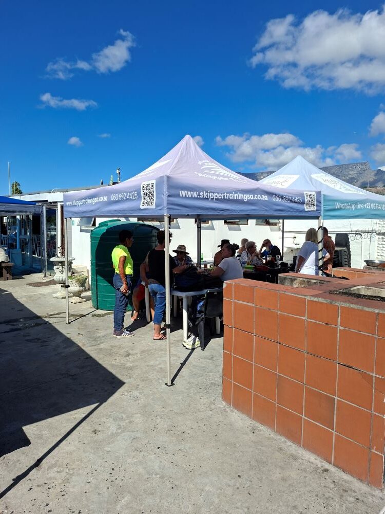 Wild Buggers Beach Buggy Club members enjoying a social gathering under branded gazebos with Table Mountain in the background at Oceana Power Boat Club.