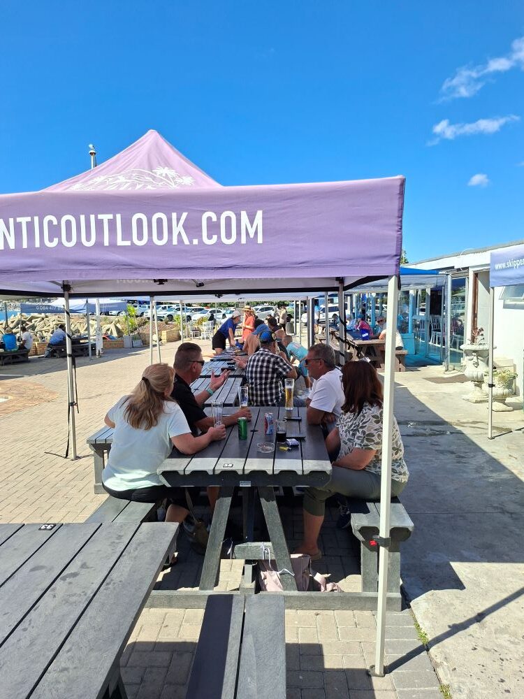 Wild Buggers Beach Buggy Club members enjoying a social gathering at long picnic tables under gazebos at the Oceana Power Boat Club in Cape Town.