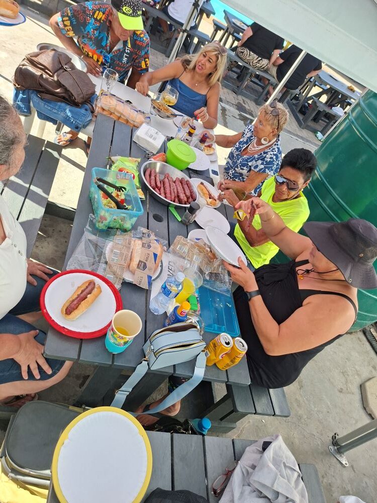 Wild Buggers Beach Buggy Club members dishing up fresh boerewors rolls and salads at a picnic table at the Oceana Power Boat Club.