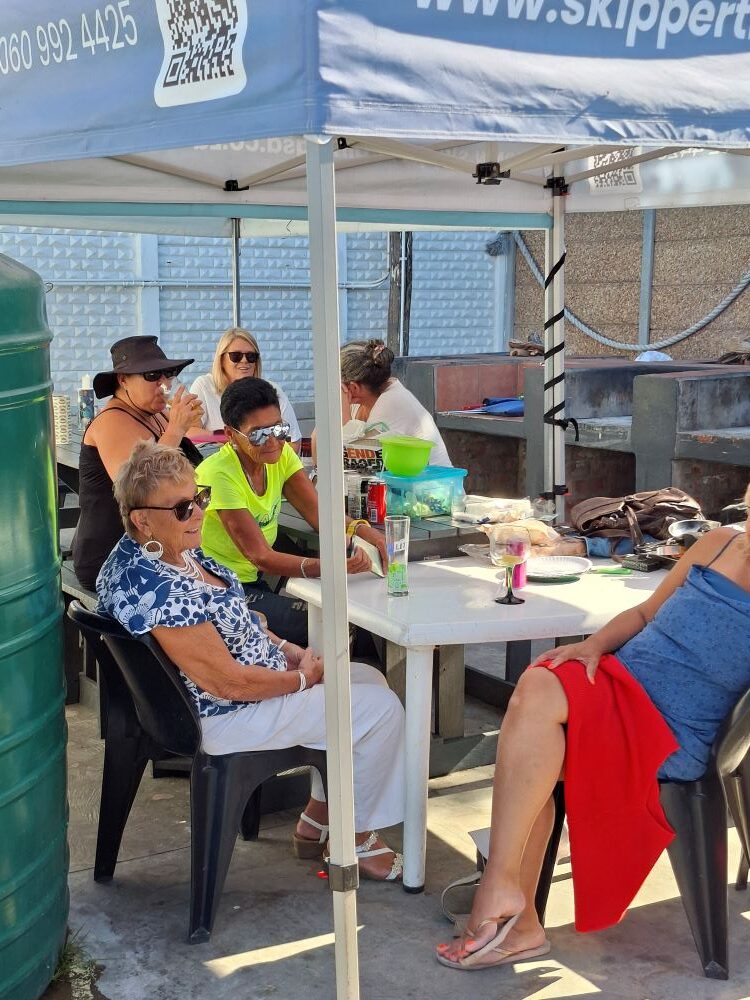 Wild Buggers Beach Buggy Club members relaxing in the shade of a gazebo at the Oceana Power Boat Club social event in Cape Town.