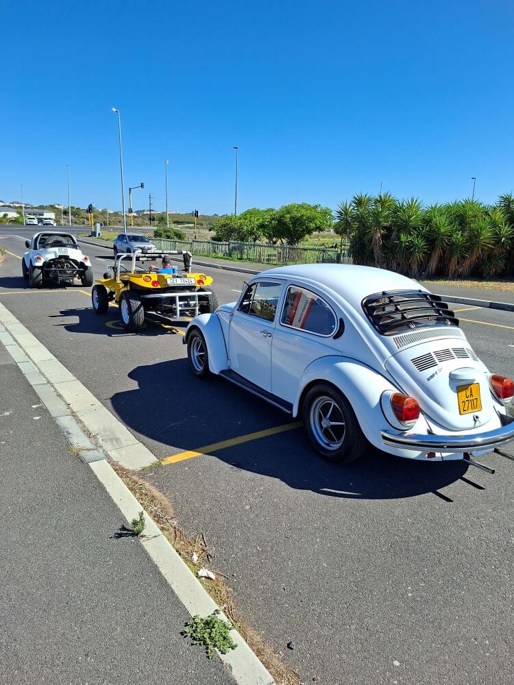 Andre and Jo-ann Gericke’s classic white 1975 VW Beetle with rear window louvers driving during a Wild Buggers club run in Cape Town.