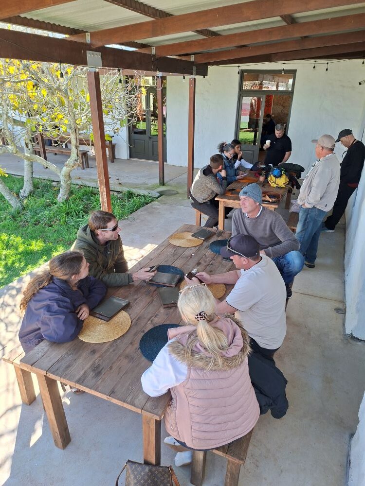 Wild Buggers members relaxing at a table and ordering coffee at !Khwa ttu before the tour during the West Coast cultural experience Run, enjoying a laid-back break at the San Heritage Centre.