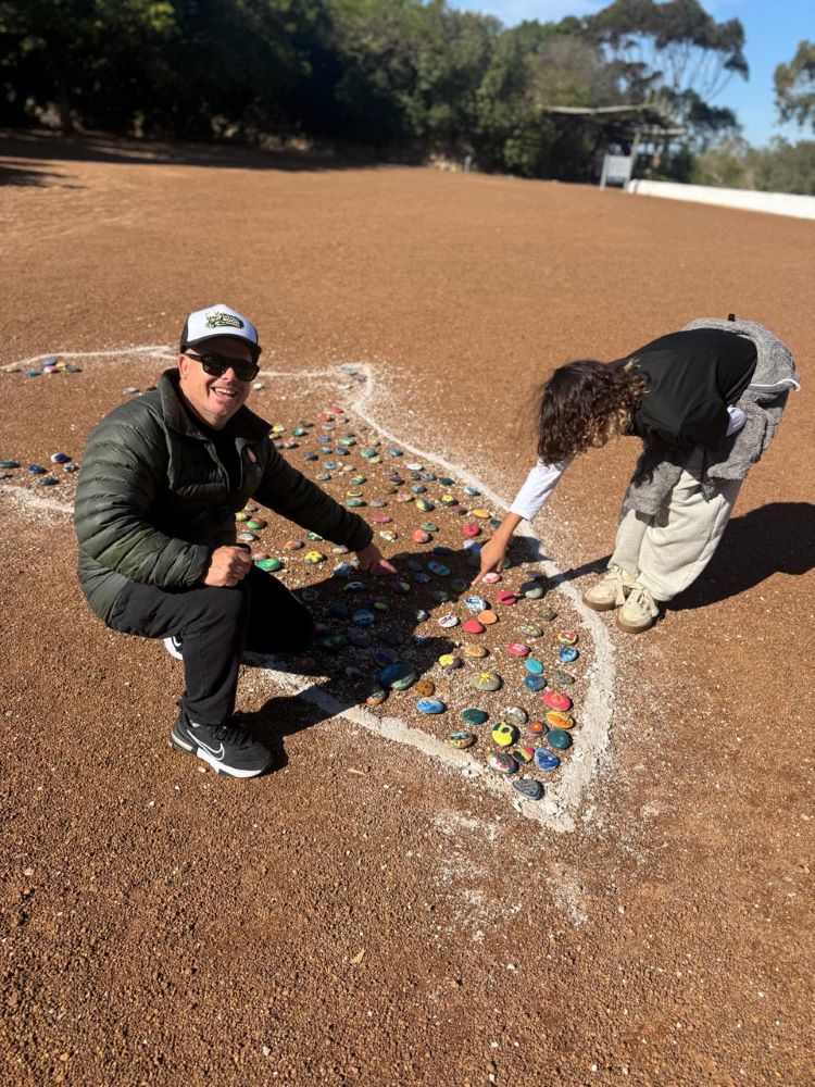 Neil and Maddox placing their painted stones into the Africa-shaped ground artwork at !Khwa ttu during the Wild Buggers West Coast cultural experience Run at the San Heritage Centre.