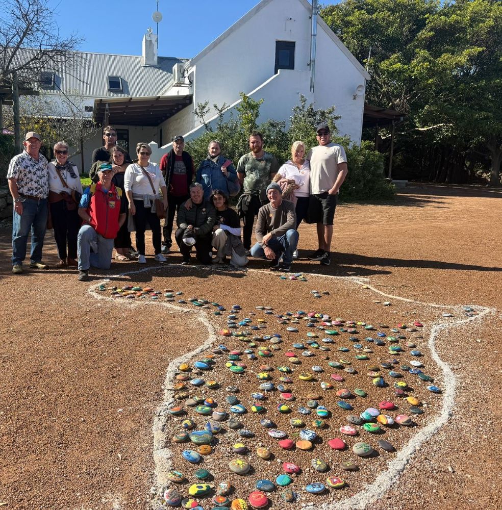 Wild Buggers members posing for a group photo at the Africa-shaped stone artwork at !Khwa ttu during the West Coast cultural experience Run, surrounded by the painted stones added at the San Heritage Centre.