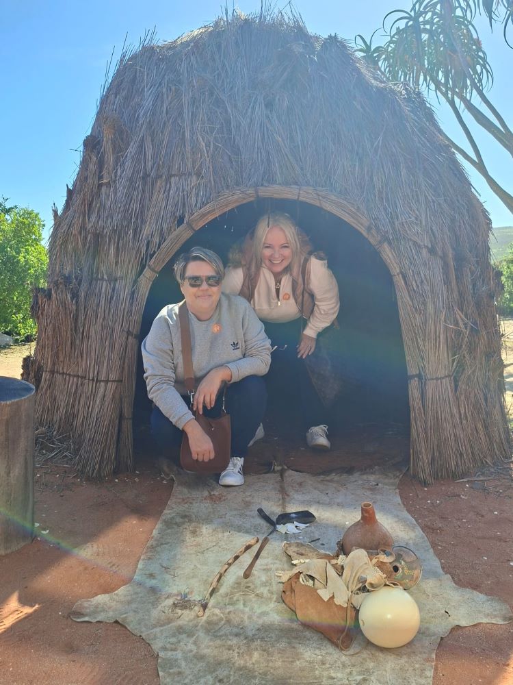 Yolande and Sam posing inside a traditional bushman hut at !Khwa ttu during the Wild Buggers West Coast cultural experience Run, enjoying one of the cultural displays at the San Heritage Centre on the West Coast.