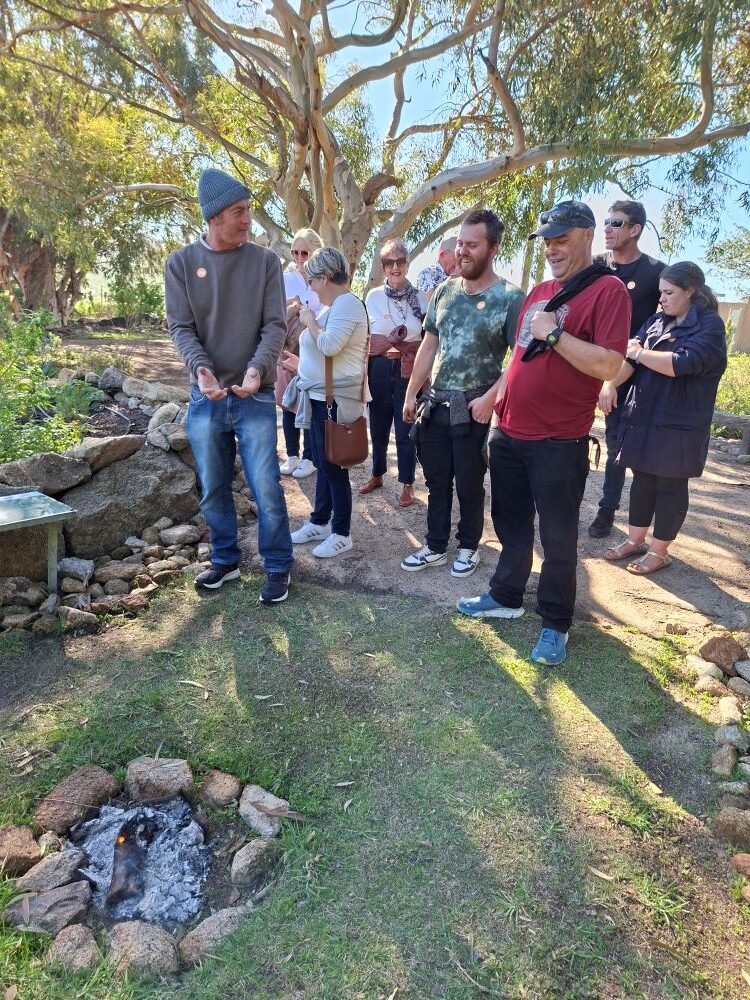 Rhoodie standing by a traditional firepit in the medicinal dagga garden display at !Khwa ttu during the Wild Buggers West Coast cultural experience Run at the San Heritage Centre.