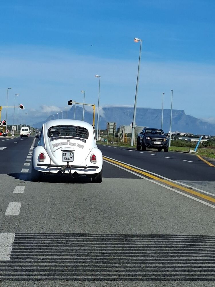 A view from behind the steering wheel showing Bertus driving his custom vehicle ahead in the convoy on the coastal road during the Wild Buggers West Coast cultural experience Run toward Melkbosstrand.