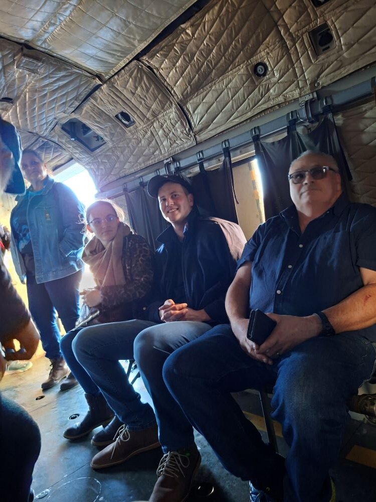 Wild Buggers car club members smiling while sitting inside the insulated cabin of a vintage Aérospatiale SA 321 Super Frelon heavy transport helicopter during a museum outing.