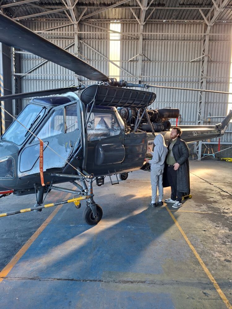 Wild Buggers club members admiring a vintage Westland Wasp HAS Mk 1 naval helicopter inside a hangar at the South African Air Force Museum during a classic car cruise.