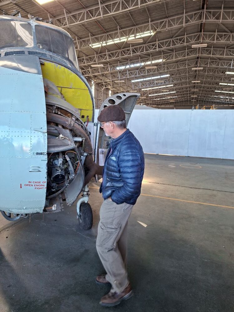 Wild Buggers club member Johann Buitendag inspecting the open nose engine compartment of a vintage Westland Wessex helicopter at the South African Air Force Museum during a classic car cruise.