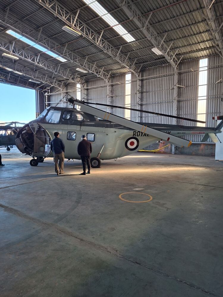 Wild Buggers club members viewing a vintage Royal Navy Westland Wessex helicopter inside a hangar at the South African Air Force Museum during a classic car cruise.