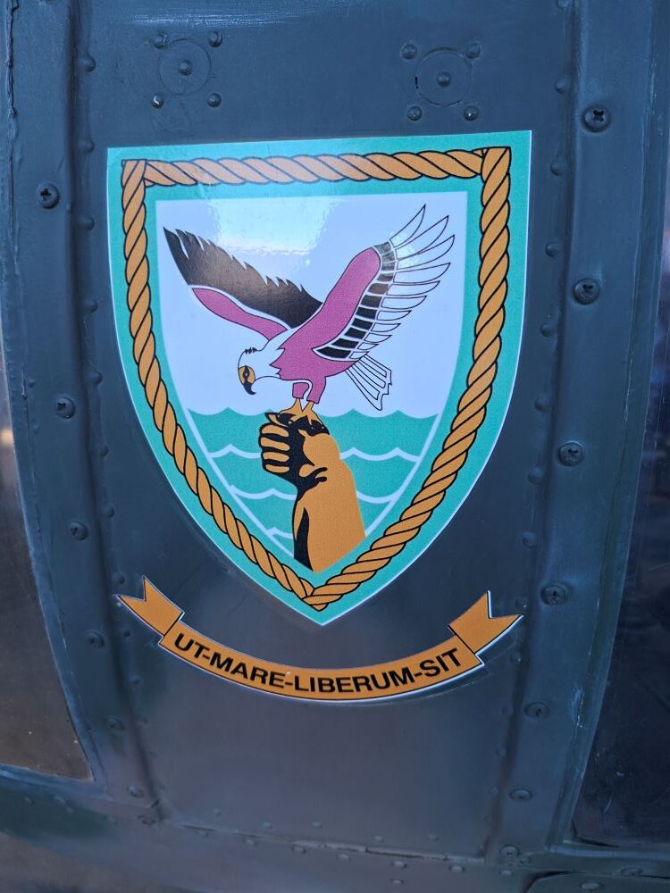 A close-up of the official 22 Squadron military emblem featuring an osprey and the Latin motto Ut Mare Liberum Sit on a vintage SAAF helicopter during a classic car club cruise.