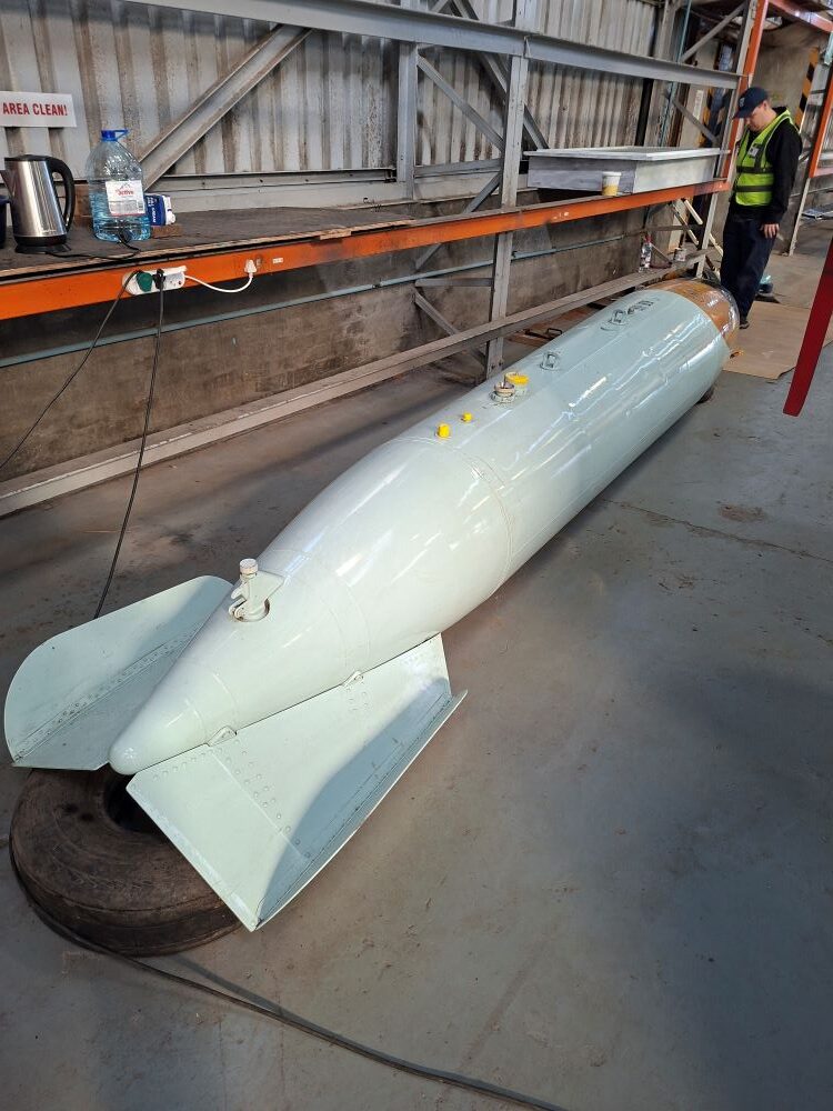 A large vintage aerial bomb ordnance display inside the workshop hangar at the South African Air Force Museum during a Wild Buggers classic car club run.