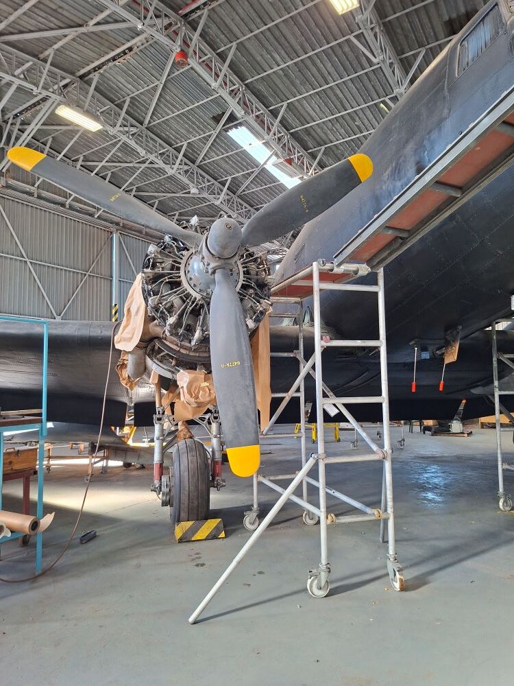 A vintage twin engine Douglas C47 Dakota transport aircraft undergoing restoration inside a hangar at the South African Air Force Museum during a classic car club cruise.