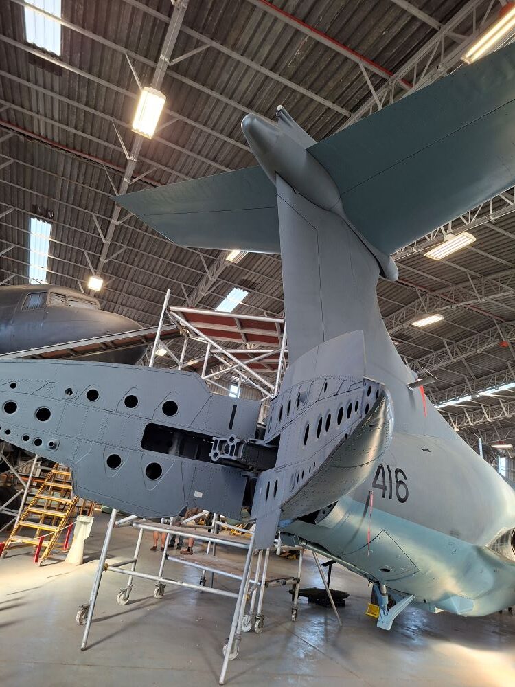 The rear tail section and open split tailcone airbrake of a vintage Blackburn Buccaneer strike aircraft with tail number 416 on display inside a hangar at the South African Air Force Museum during a classic car club run.