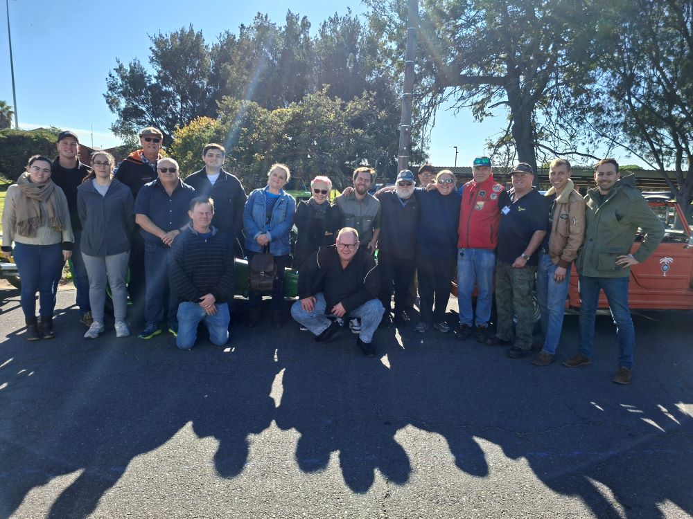 A large group photo of the Wild Buggers club members alongside passionate museum volunteers standing in front of custom beach buggies and classic VW air-cooled vehicles during a winter cruise.