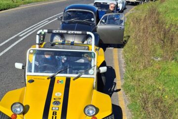 A line of custom beach buggies, Baja Bugs, and classic VW air-cooled vehicles pulled over on the side of a country road for a catch-up stop during a club winter cruise.