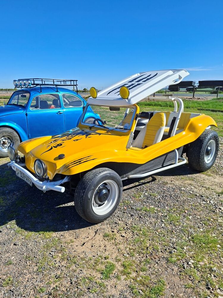 A bright yellow custom Beach Buggy, known as Zara's Buggy, parked next to a classic VW Beetle during the Wild Buggers club Propellers and Pistons Winter Cruise, highlighting our passion for air-cooled vehicles.