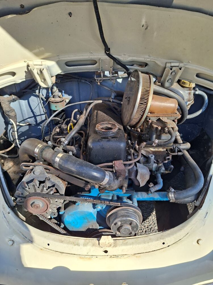 A close-up view of a modified A15 Datsun motor fitted into the engine bay of a classic VW Beetle, showcased during the Propellers and Pistons Winter Cruise with other beach buggies, Baja Bugs, and classic VW air-cooled vehicles.