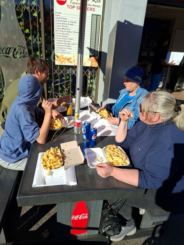 Club members enjoying a well-deserved feast of fish and chips at Cape to Rio Fisheries after the Propellers and Pistons Winter Cruise, an event celebrating custom beach buggies, Baja Bugs, and classic VW air-cooled vehicles.
