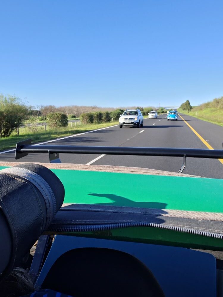 A view from the road looking back at Heinrich and Herbie following in their classic VW air-cooled Beetle as we travel home after the Wild Buggers Beach Buggy Club Propellers and Pistons Winter Cruise, an event packed with custom Beach Buggy and Baja Bug vehicles.