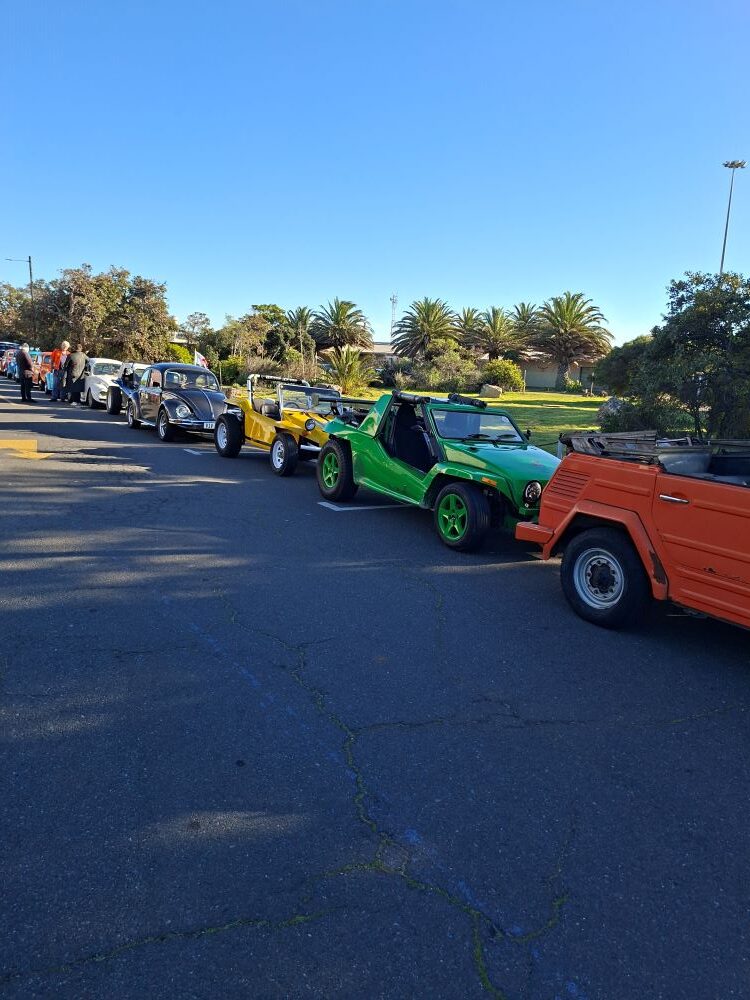A line of custom beach buggies and classic VW Beetles parked in prime spots outside the South African Air Force Museum during a Cape Town car club run.
