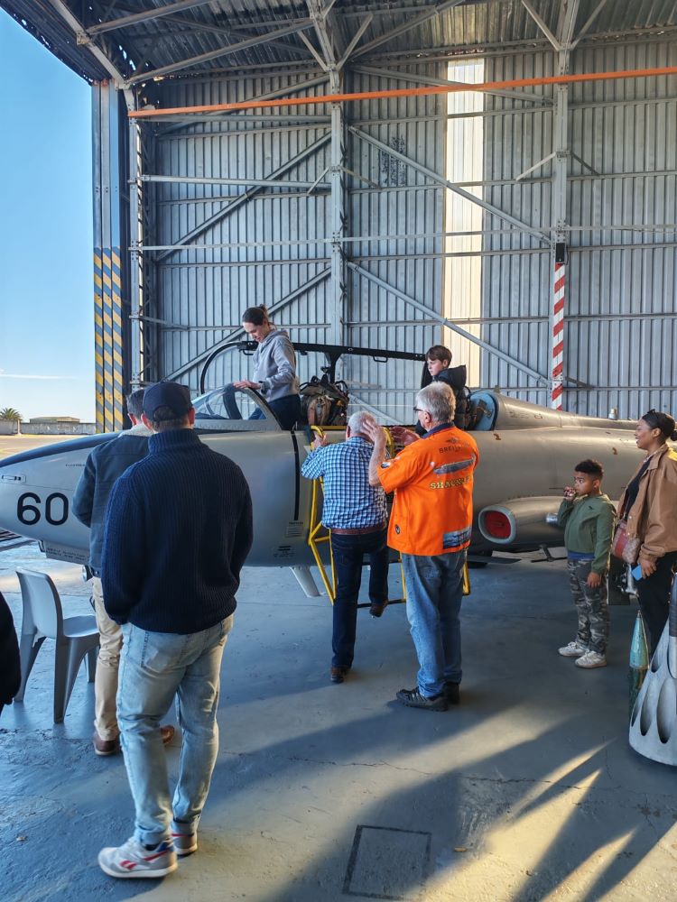 Wild Buggers club members examining a vintage Atlas Impala jet aircraft inside a hangar at the South African Air Force Museum during a classic VW air-cooled vehicle cruise.