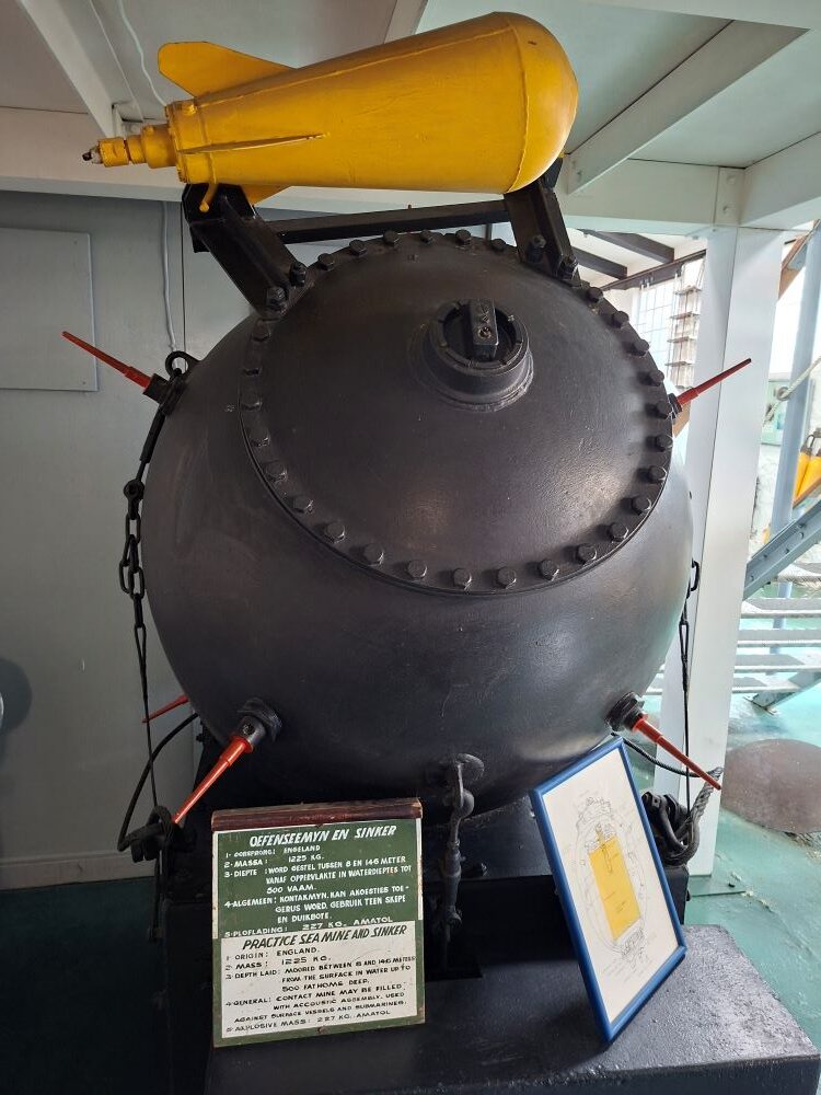 A historical practice sea mine and sinker display complete with informational plaque inside the South African Naval Museum.