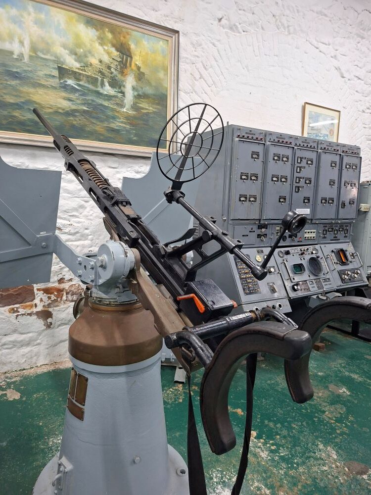 A vintage Browning .303 anti-aircraft machine gun mount with shoulder rests and ring sight on display at the museum.