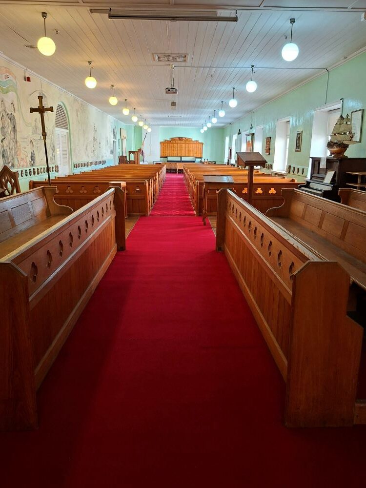 The interior nave and wooden pews leading down the red carpet inside the historic naval church.