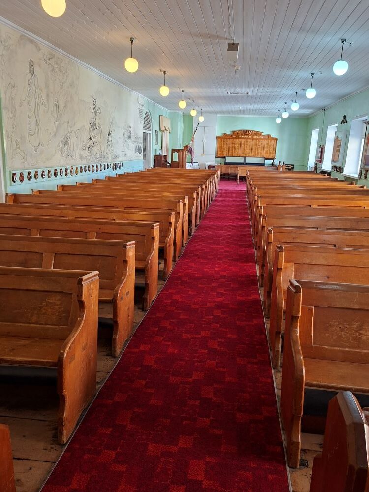 The interior view of the historic naval church showing the wooden pews and wall murals.