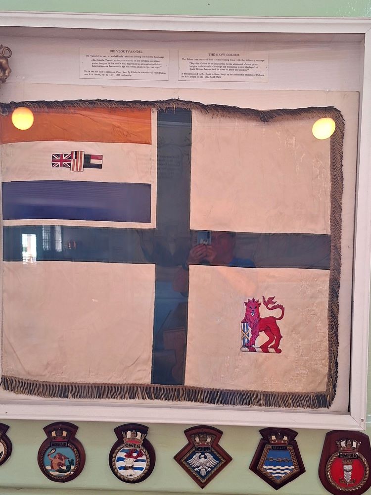 The framed South African Navy Colour flag with a red lion and naval ensign canton on display inside the historic church.