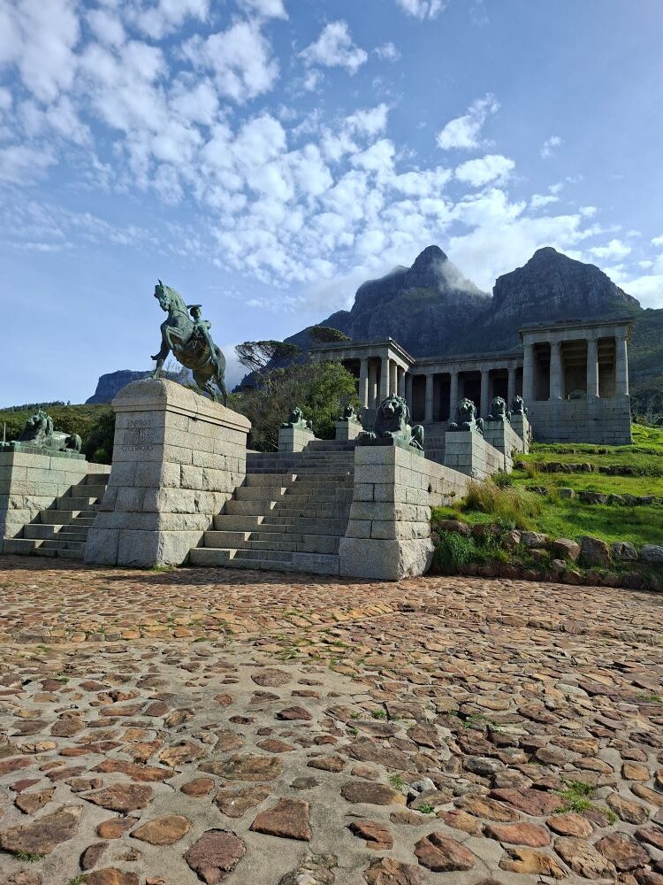 The magnificent stone architecture and statue at Rhodes Memorial framed against a dramatic mountain backdrop.