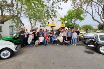 Club members posing together for a group photo next to their vehicles before departing from the stop.