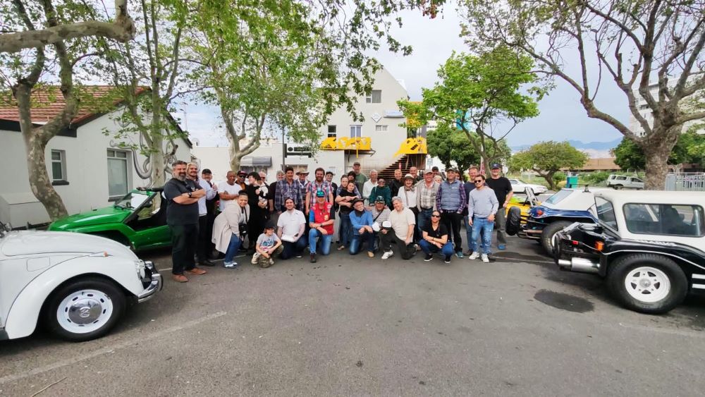 Club members posing together for a group photo next to their vehicles before departing from the stop.