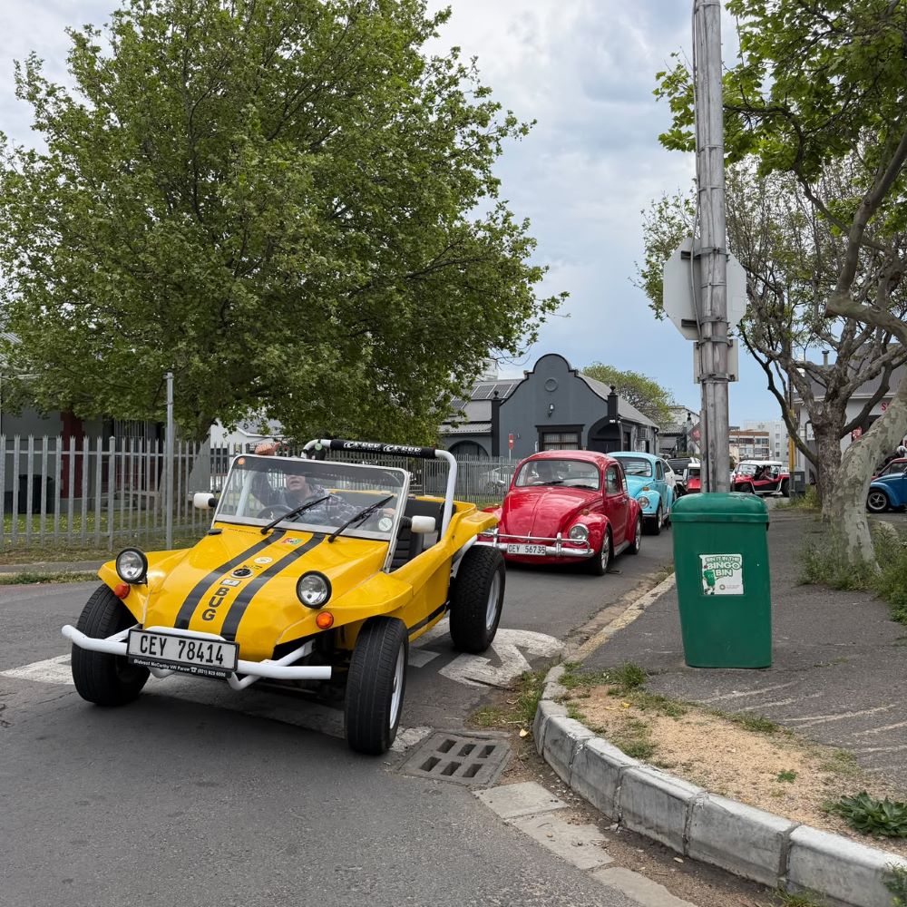 Wiehann taking the lead in a yellow beach buggy followed by a convoy of classic cars along the street