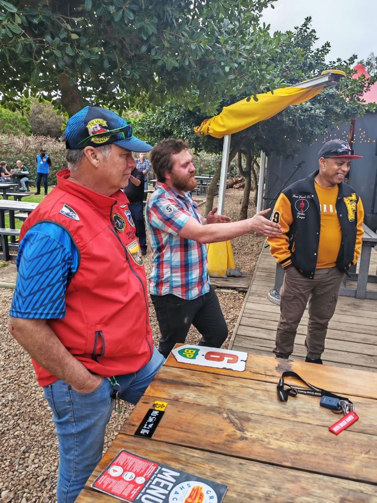 Anton and club members chatting and sharing stories together outdoors during a stop on the run.