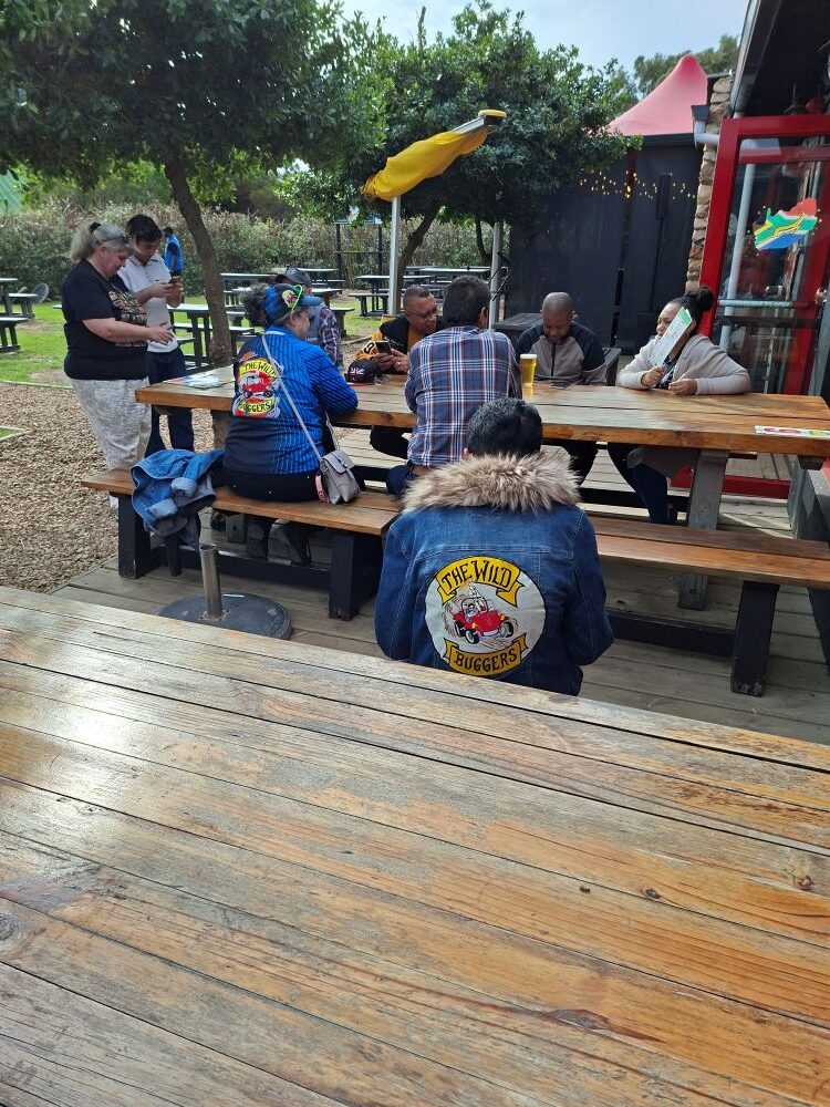 Club members seated at wooden outdoor tables while resting and waiting for ice cream during the stop.