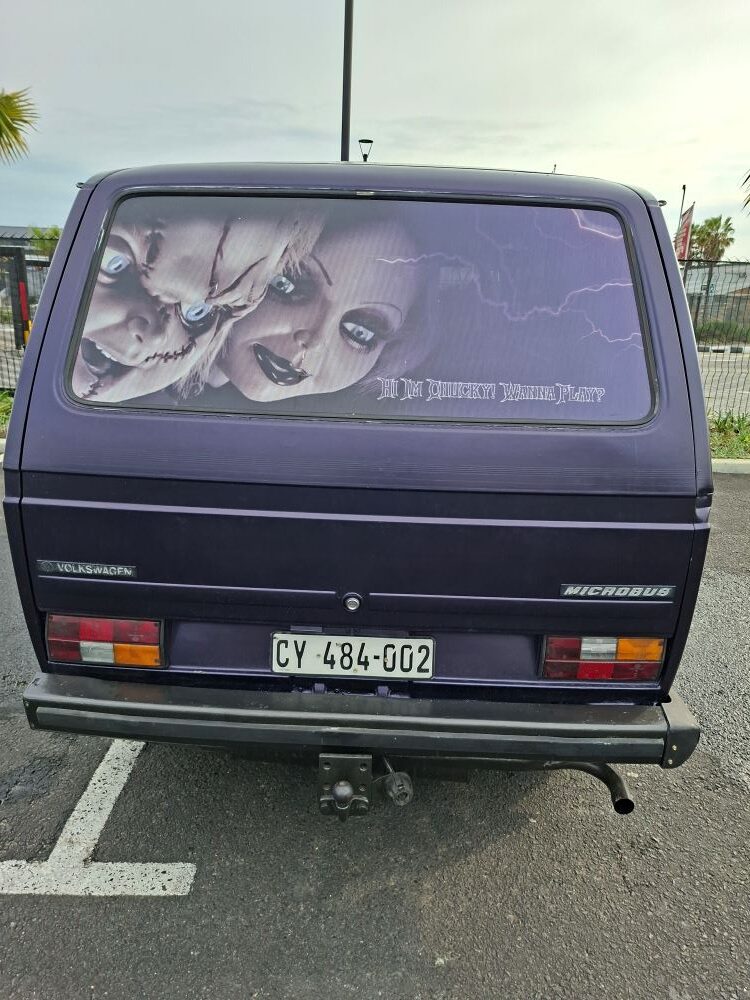 A custom Volkswagen microbus called Chucky featuring unique rear window graphics parked at the meetup point.