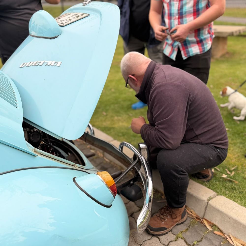 Leon Visser inspecting an engine bay during a stop at Potbelly Coffee Shop and Bakery in Klapmuts on Wiehann's Run.