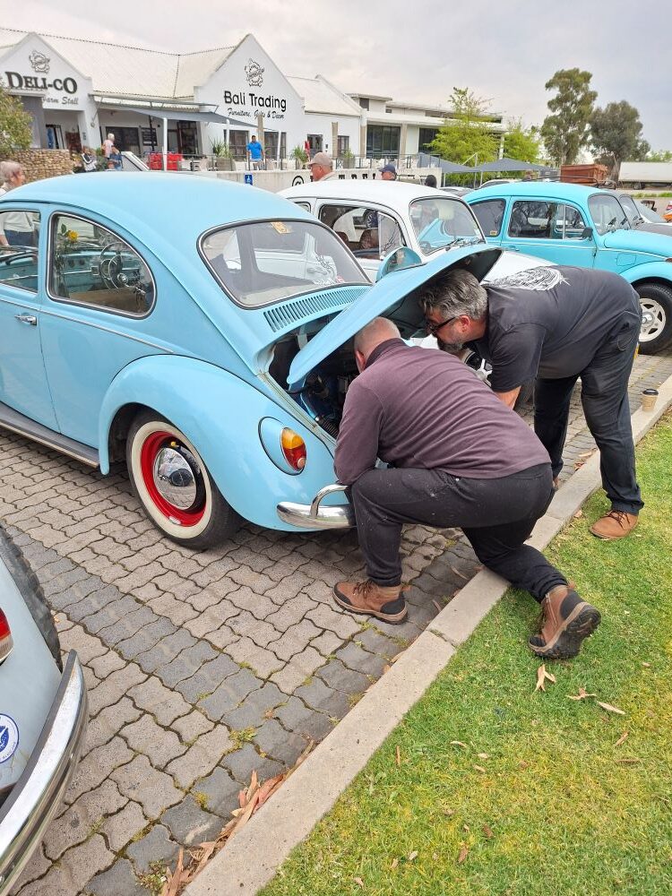 Leon Visser assisting fellow club members with a technical check on a classic car during the convoy stop.