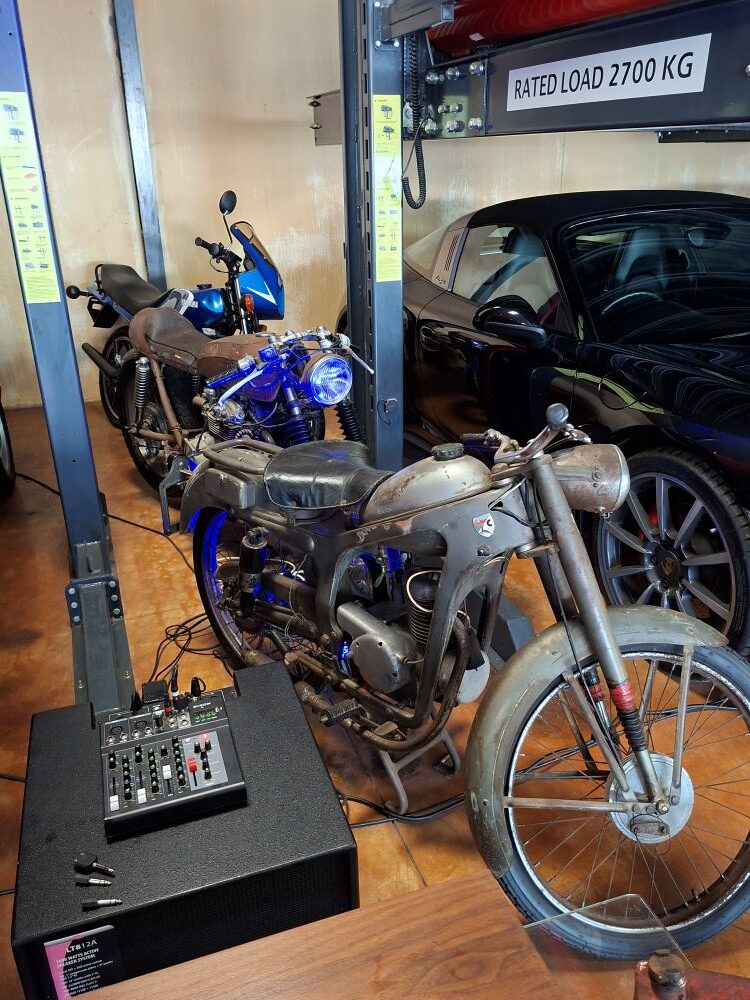 A rare vintage motorcycle on display next to a car lift inside the automotive collection at Lourensford Estate.