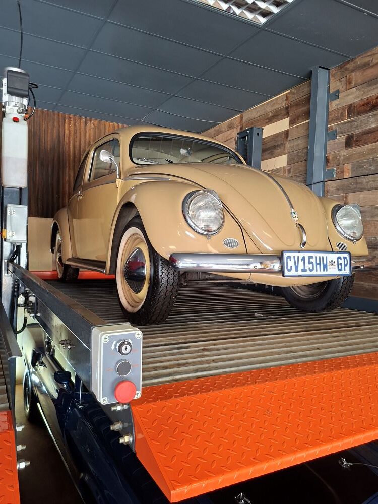 A classic air-cooled VW Beetle raised on a hydraulic lift during the club's visit to the automotive display.
