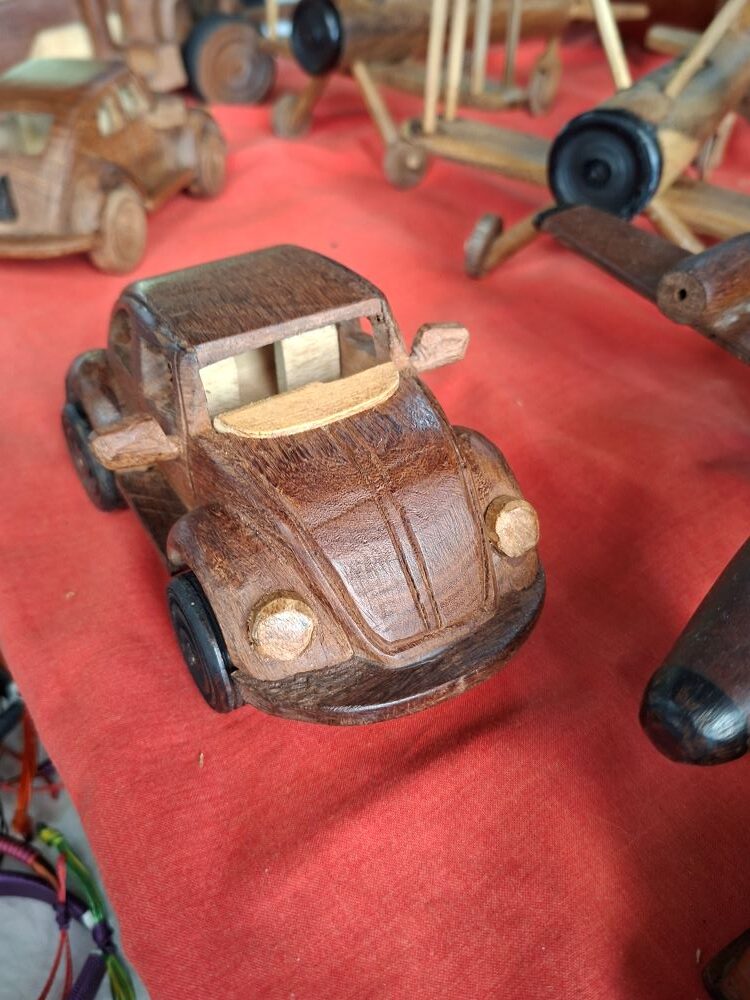 A handmade wooden model of a classic air-cooled VW Beetle carved by local artisans and displayed at the market.